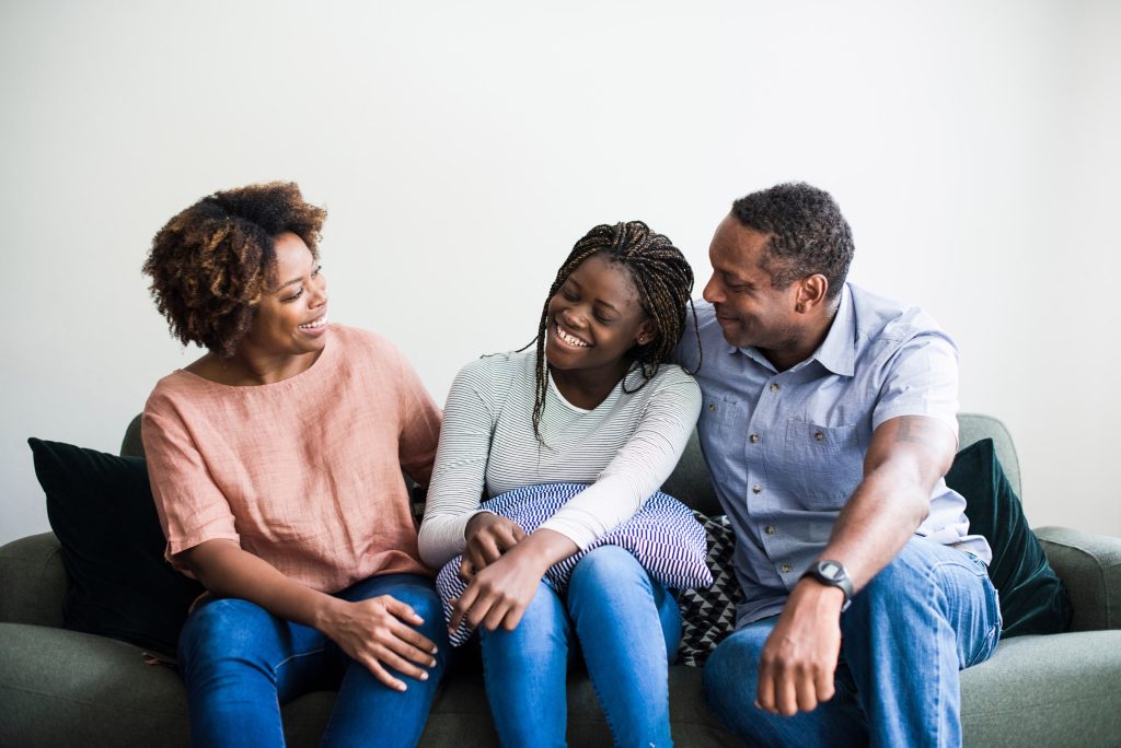 family of three laughing on couch family of three laughing on couch