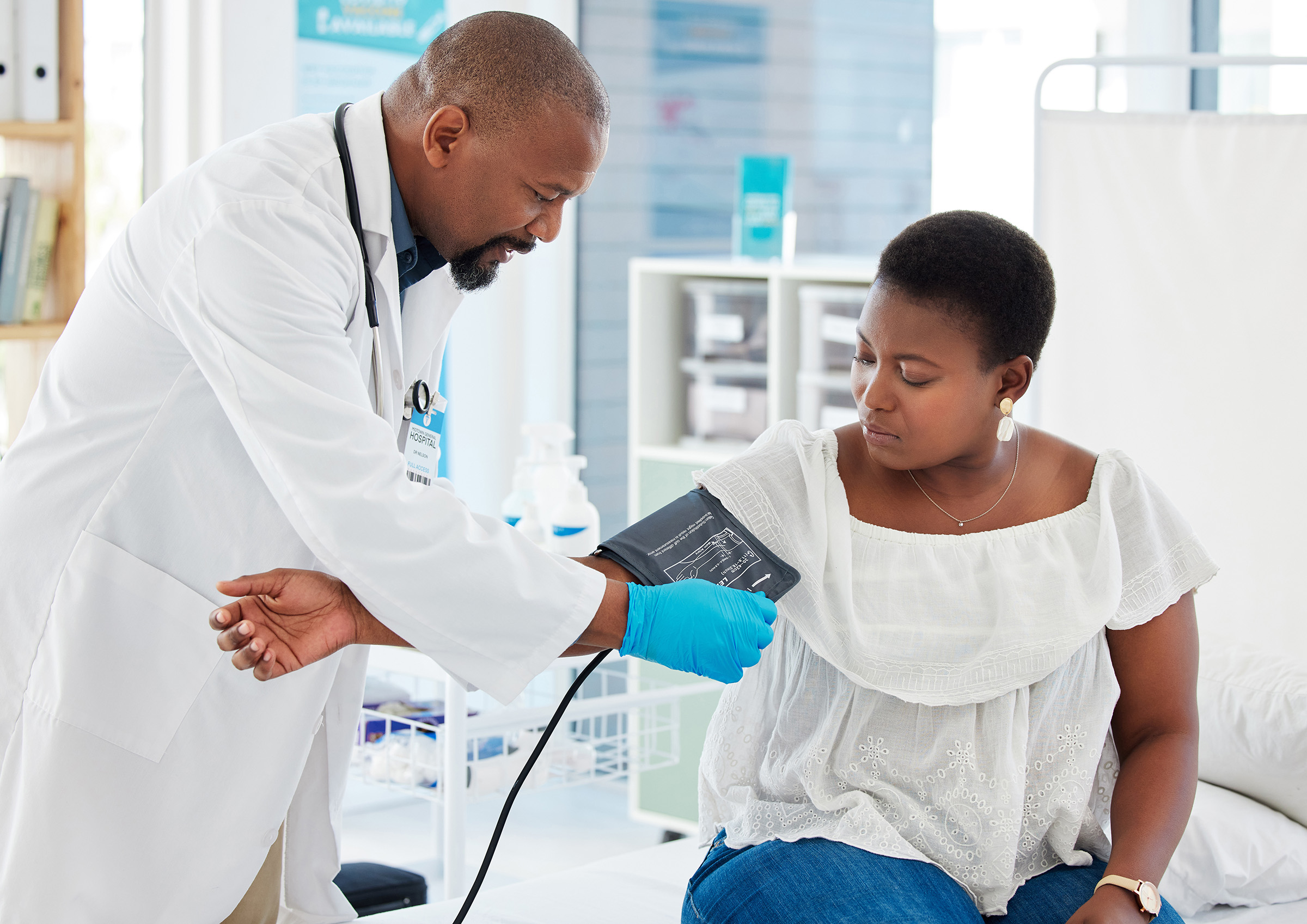 black male doctor taking blood pressure black female patient
