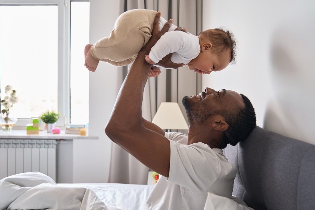 father lifting baby overhead in bedroom