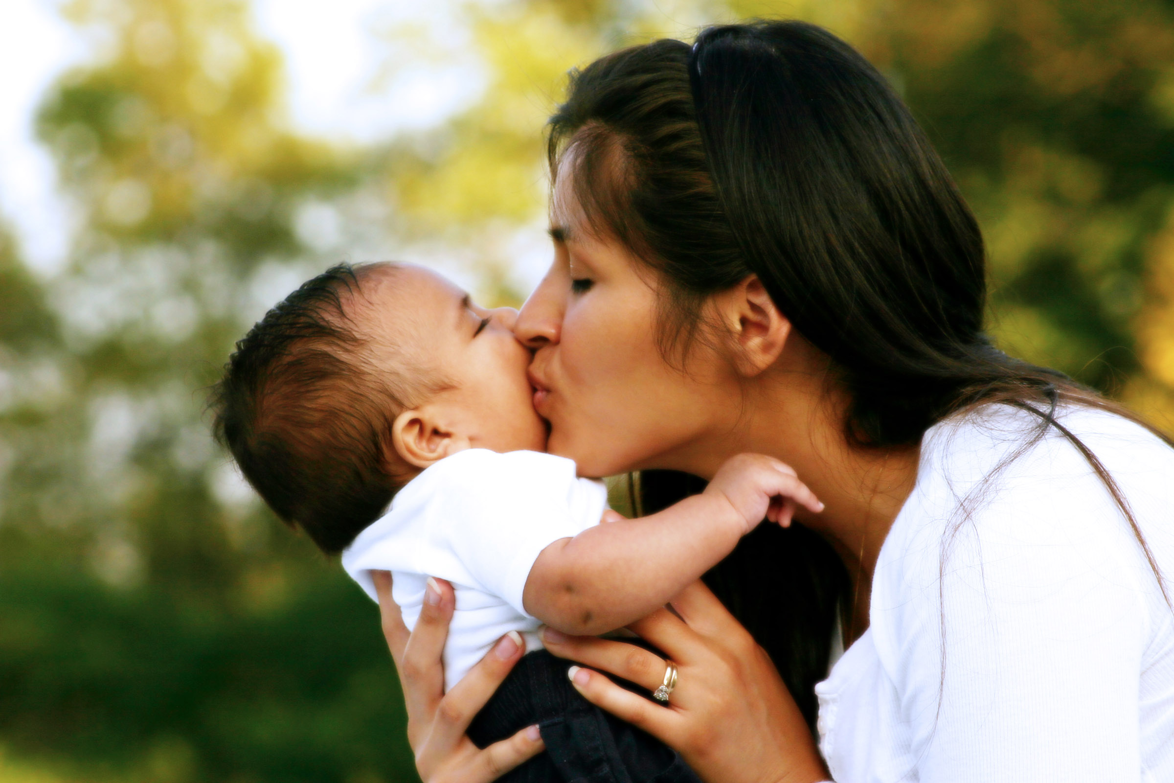 mother kissing baby outdoors in autumn
