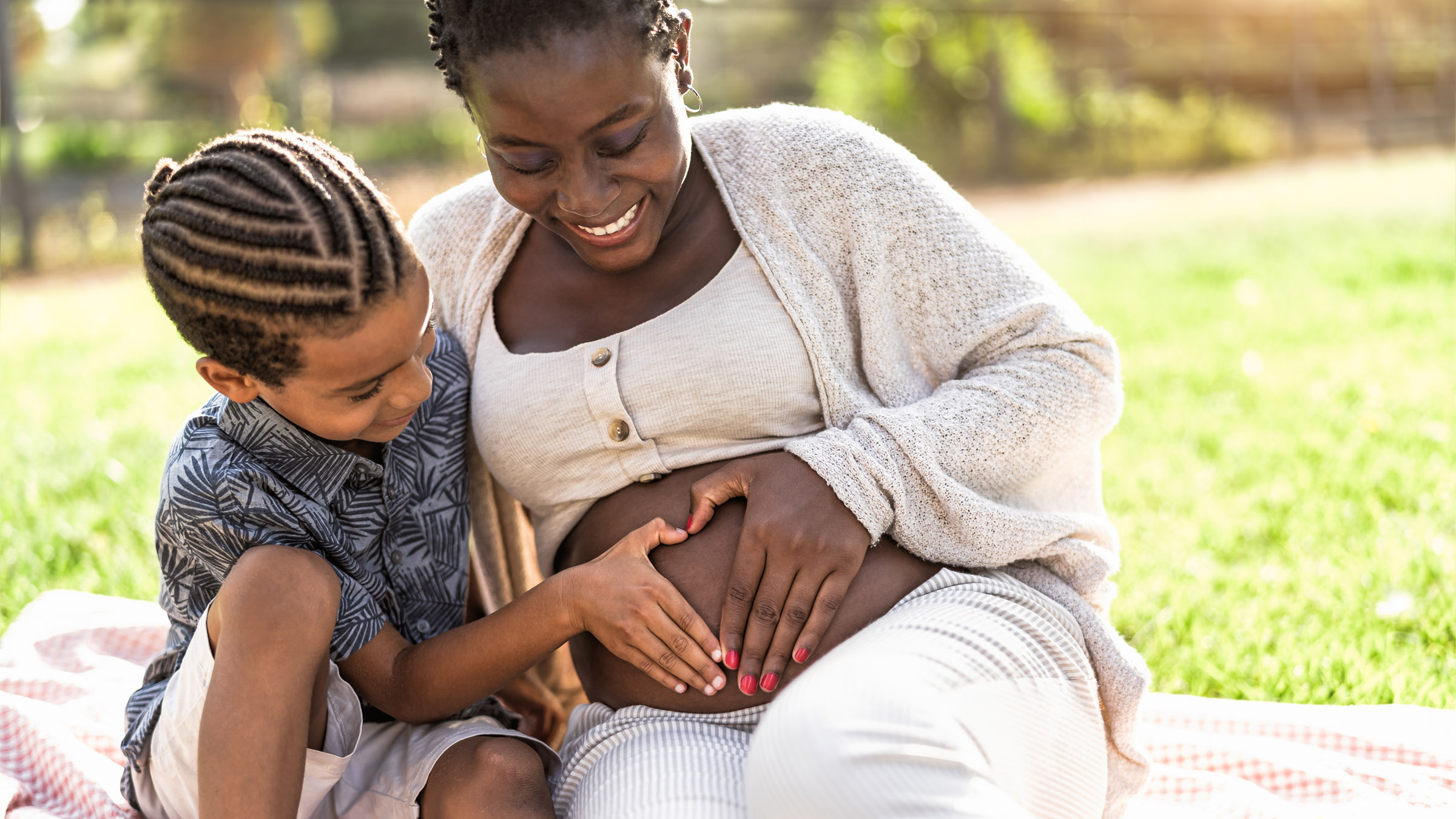 pregnant mother and son heart hands on belly outdoors