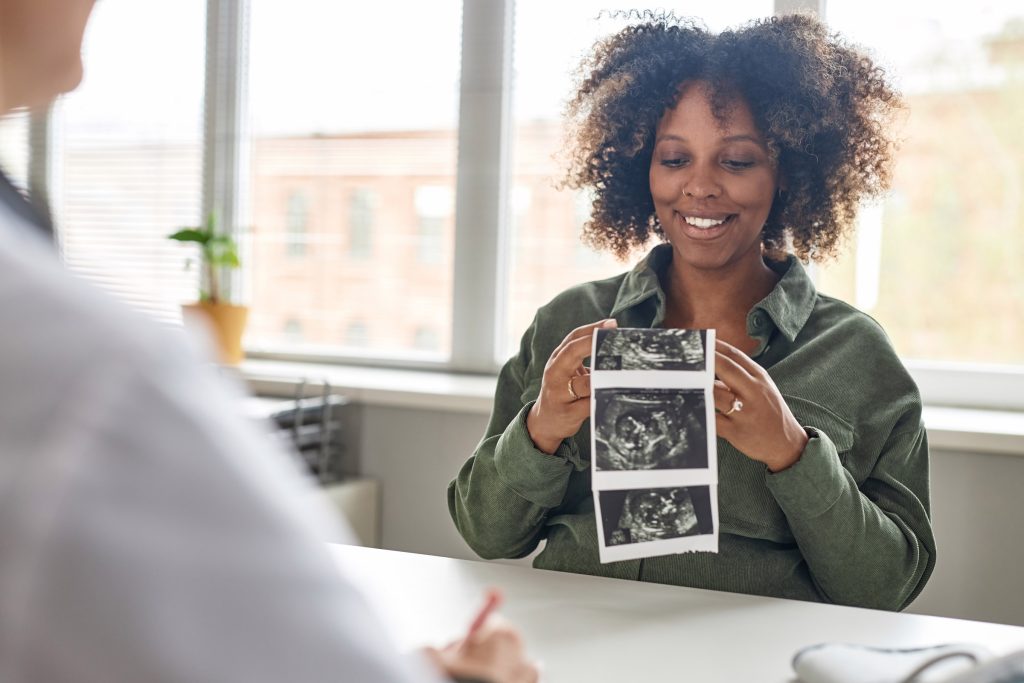 pregnant woman holding ultrasound photos